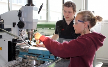 Bosch-Lehrlinge unterst&uuml;tzen M&auml;dchen, die im Zuge des Girls&acute; Days ins Bosch-Werk Hallein gekommen sind, beim Fertigen eines Briefbeschwerers an einer Fr&auml;smaschine. - Bosch &Ouml;sterreich